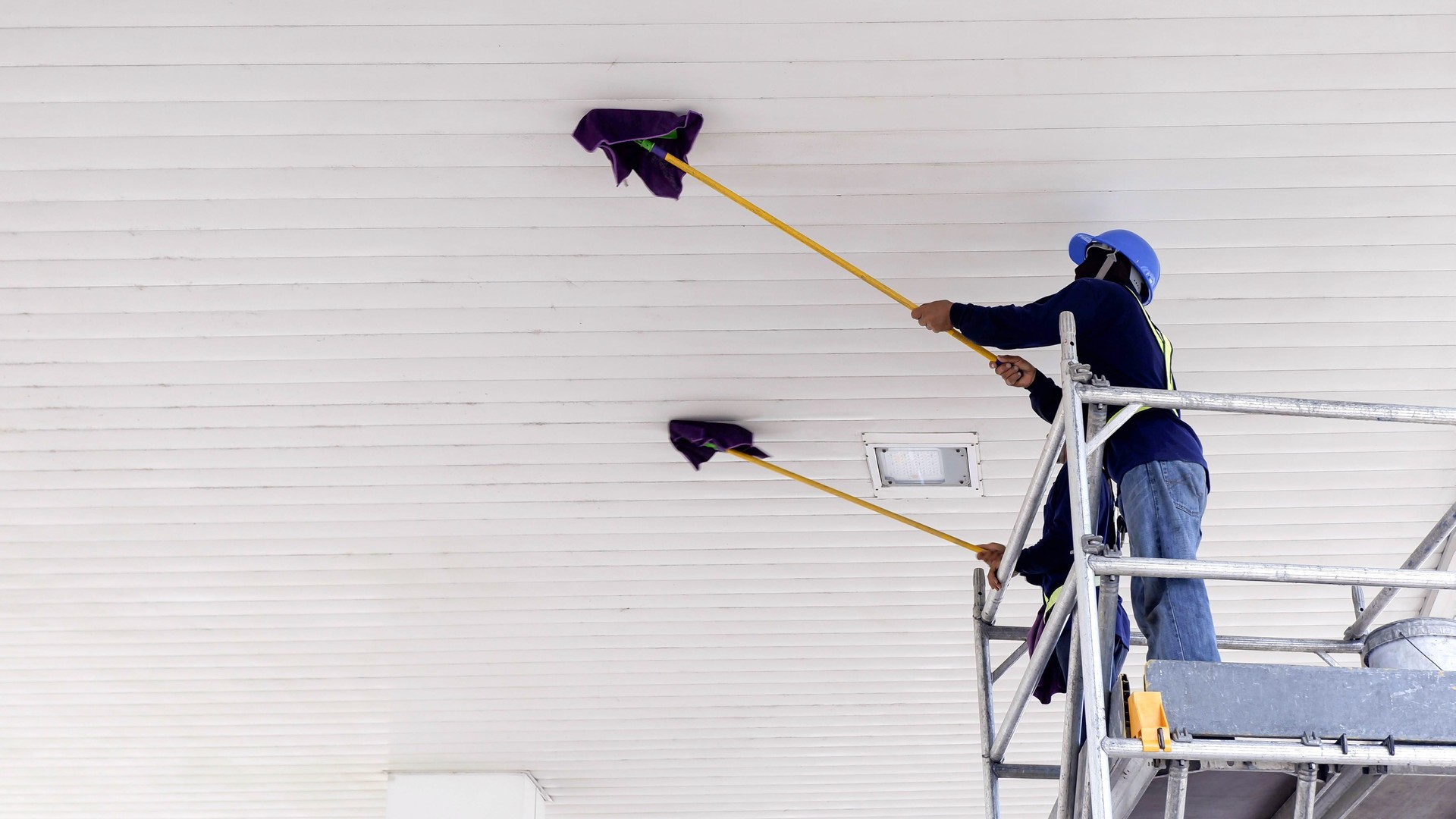 Workers cleaning ceiling of petrol station