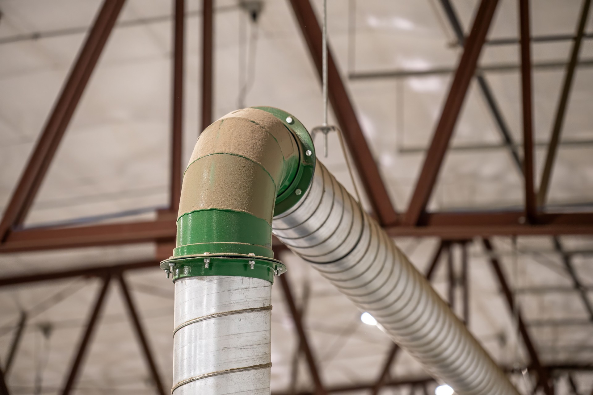 Industrial HVAC metal piping in a production facility with a coating of dust.